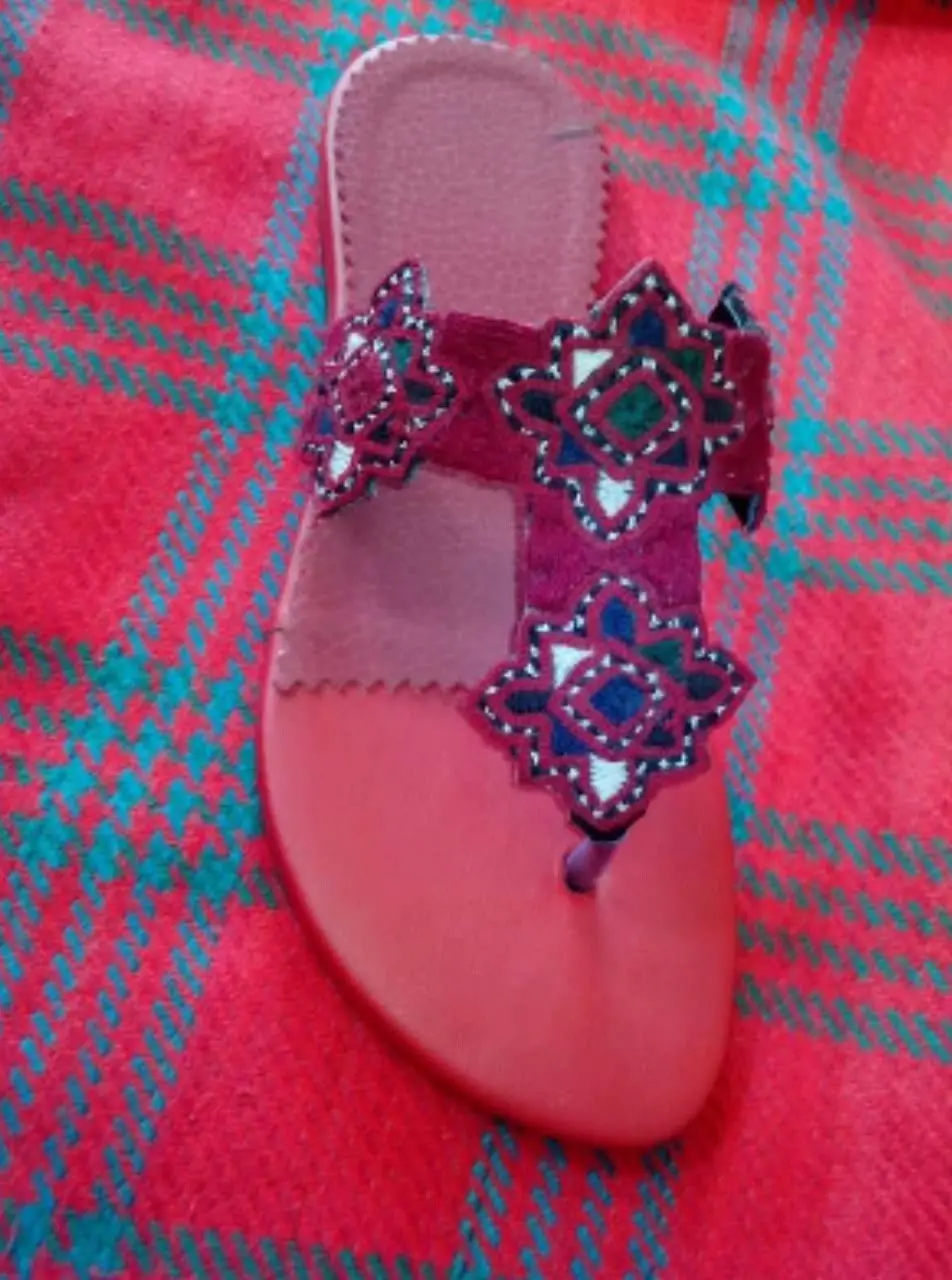One of the sandals Ehsan made: a red leather sole with hand-embroidered star panels across the strap and toe post.