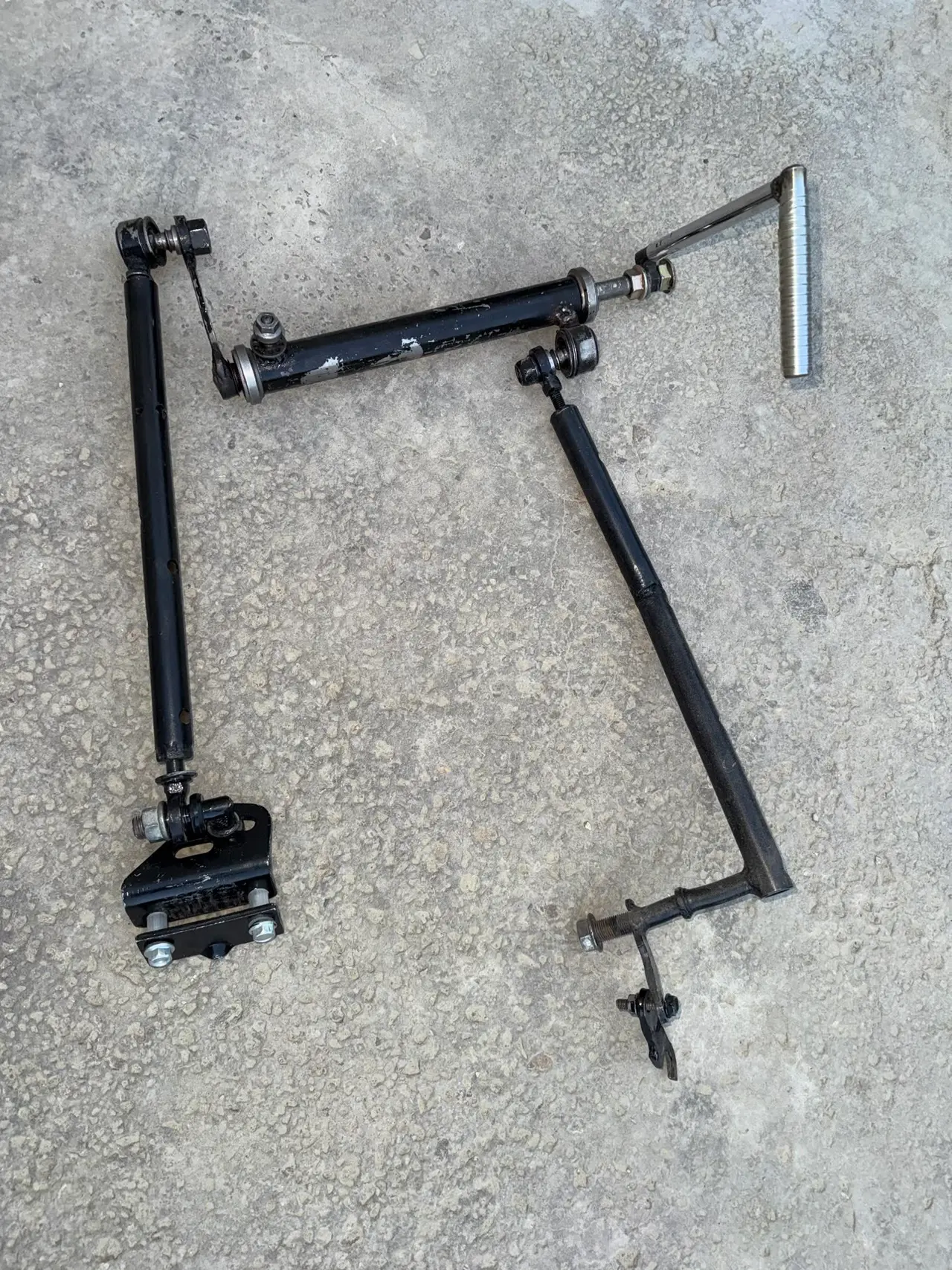 The 2025 hand control laid out in two pieces, showing the ball joints and the bracket that bolts it into the car.