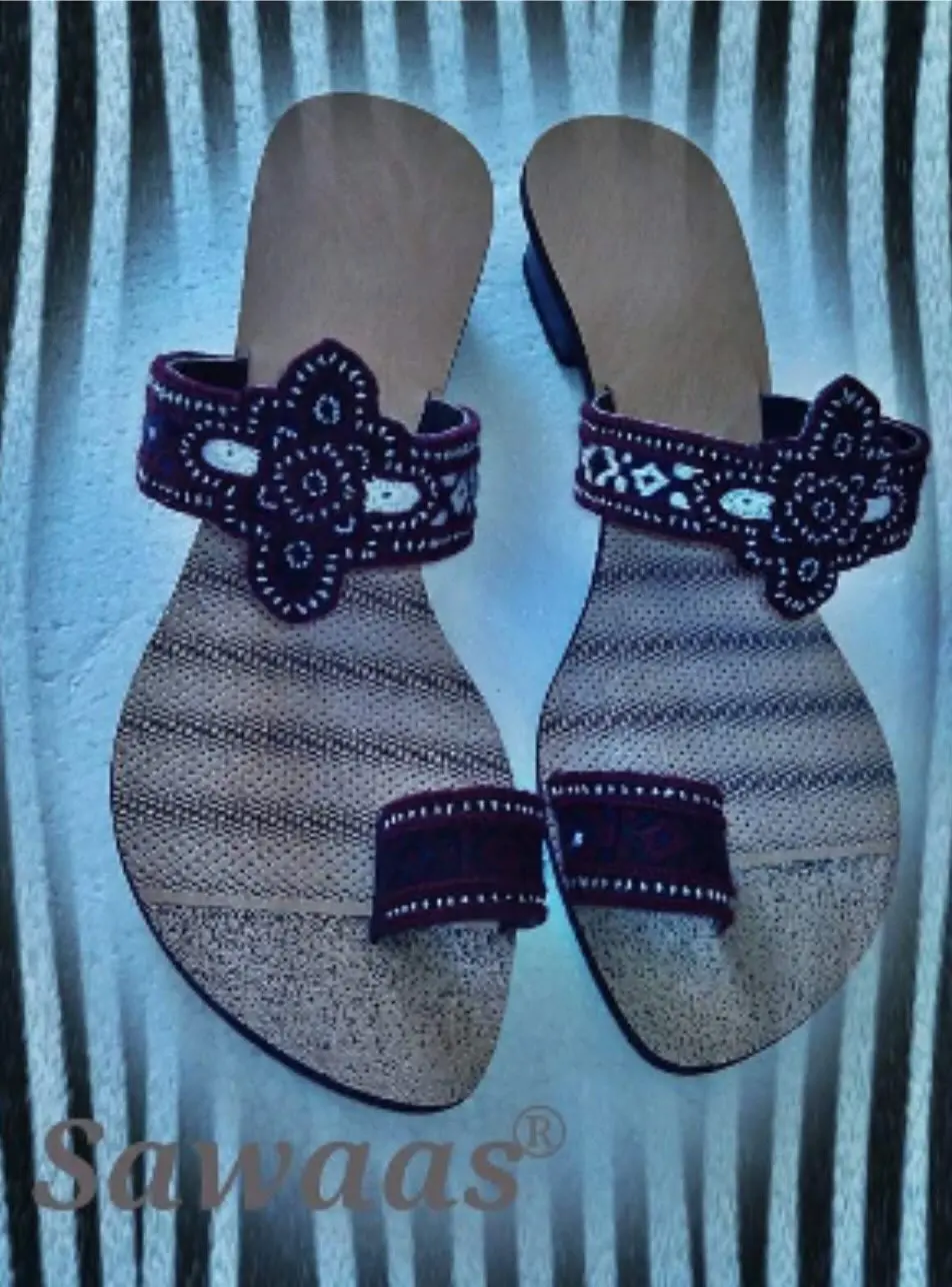 A pair of Balochi sandals Ehsan made: flat soles with wide embroidered straps, each carrying a stitched flower motif.
