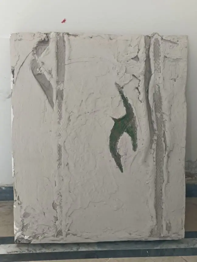 A thesis relief panel in grey plaster, with two vertical channels and a small green form set into the surface.